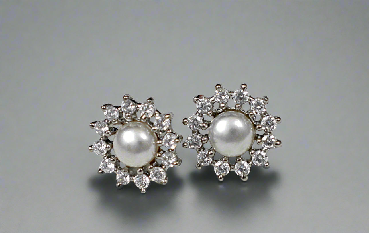Pair of pearl earrings with diamond accents on a textured gray background