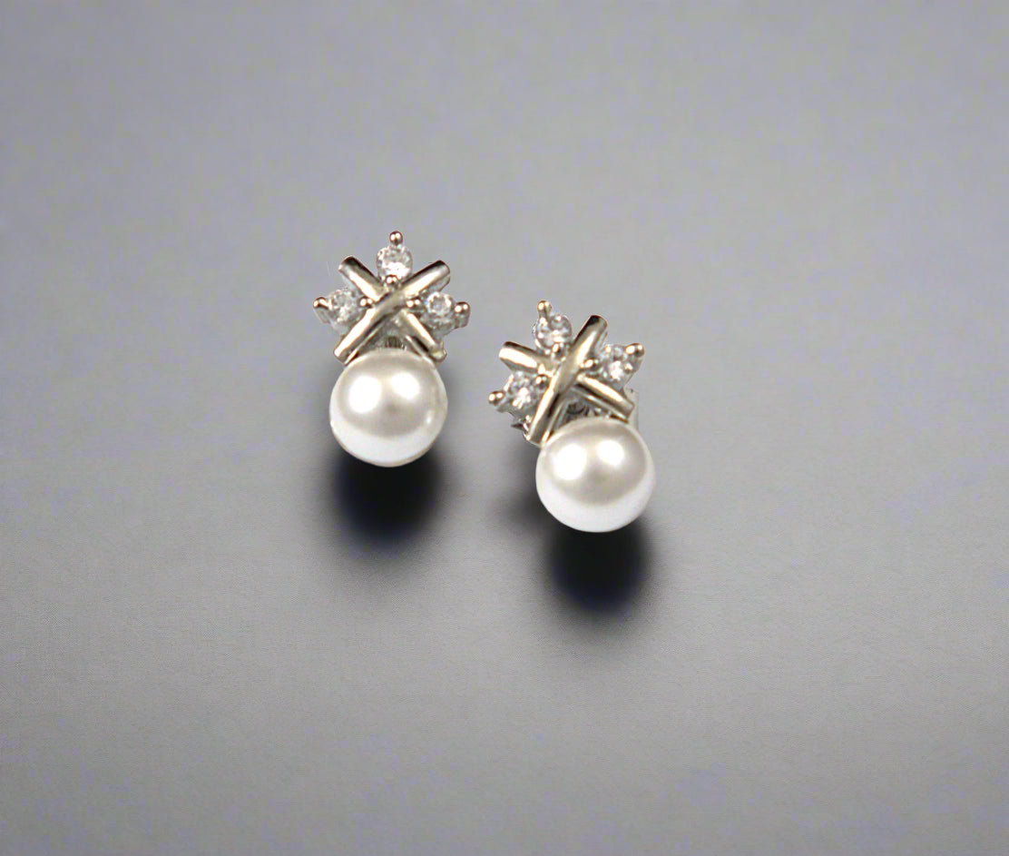 Pair of pearl earrings with star-shaped diamond tops on a white background