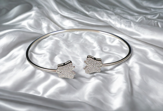 Silver bracelet with butterfly-shaped ends on a satin surface