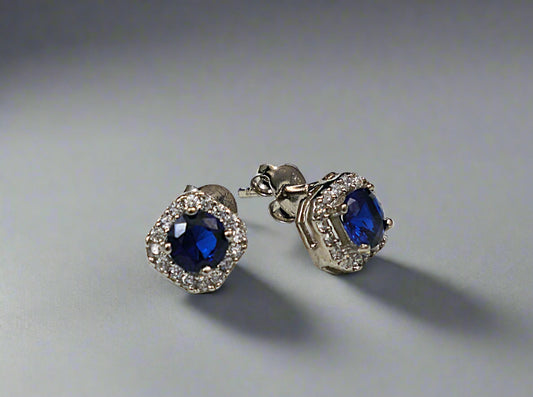 Pair of earrings with blue gemstones on a textured white surface
