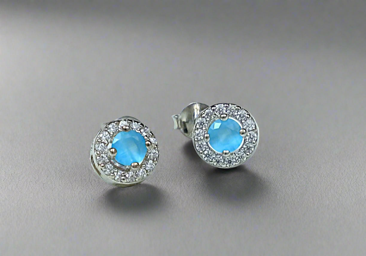 Pair of silver earrings with blue gemstones on a white marble background