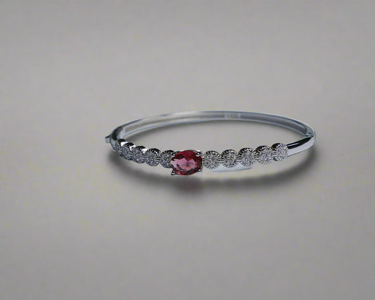 Silver bracelet with a red gemstone on a light gray background