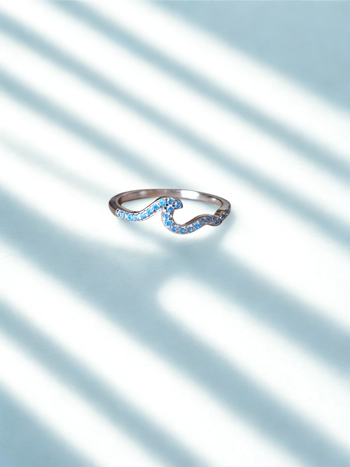 Silver ring with blue gemstones on a light blue background