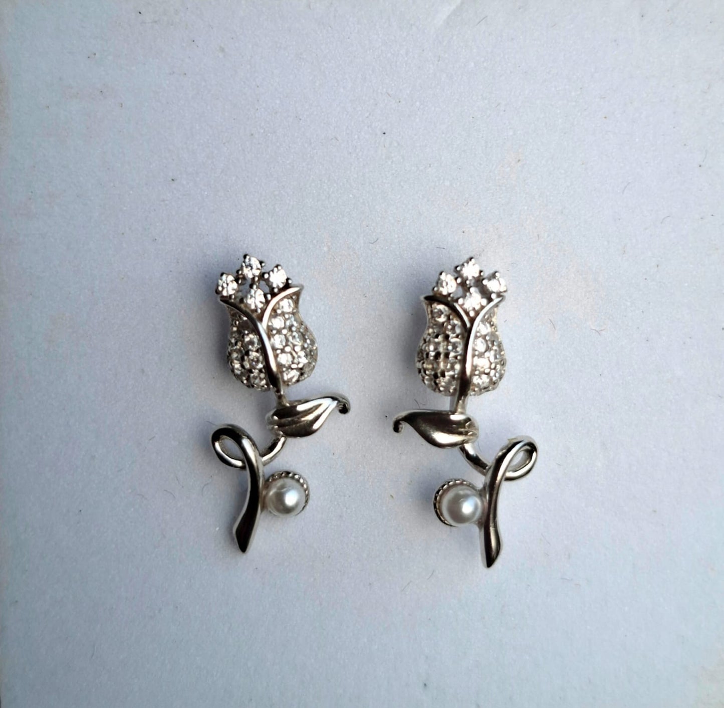 Silver tulip-shaped earrings with pearl accents on a light gray background