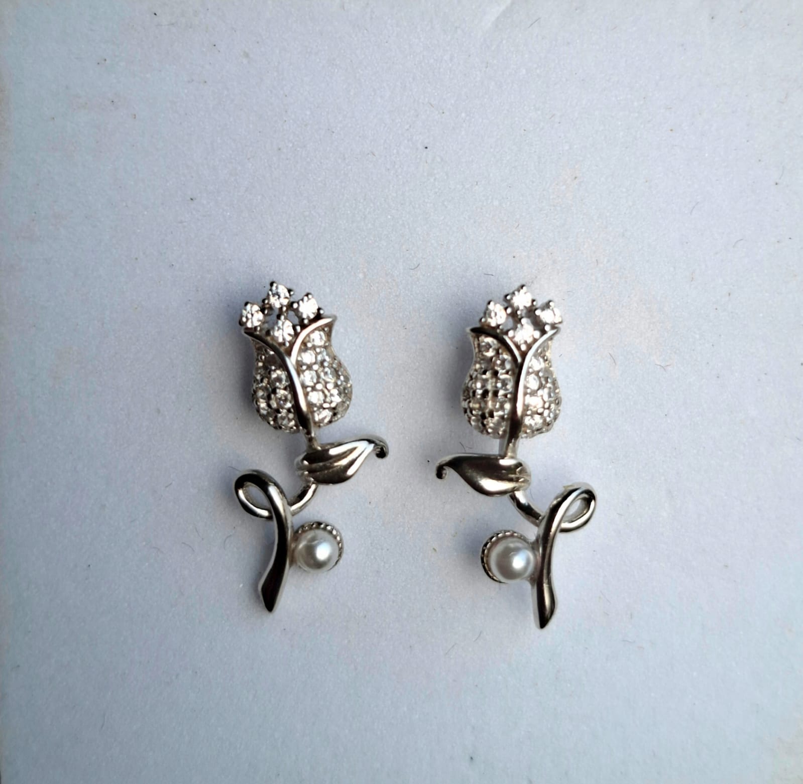 Silver tulip-shaped earrings with pearl accents on a light gray background
