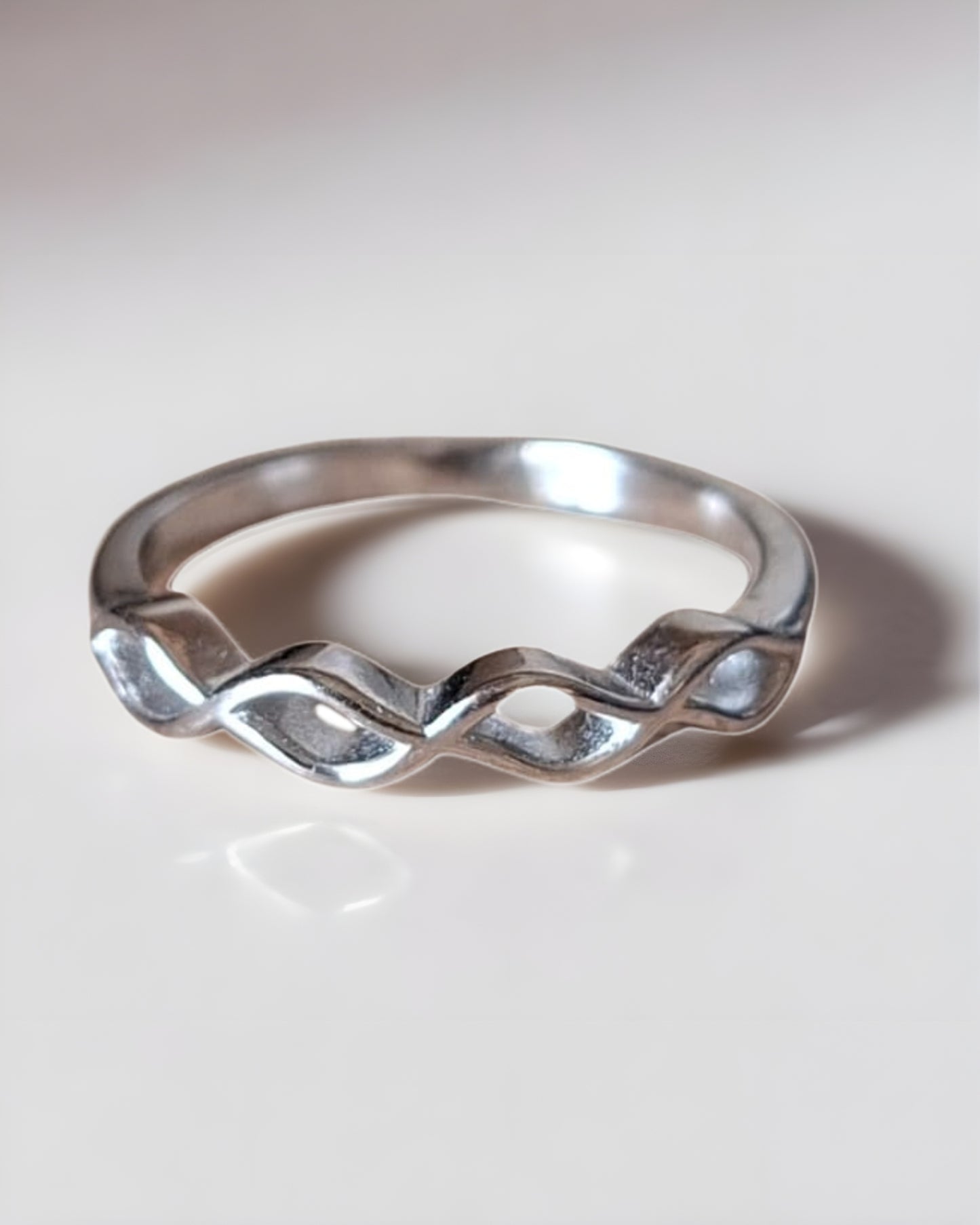 Silver ring with wavy design on a light gray background