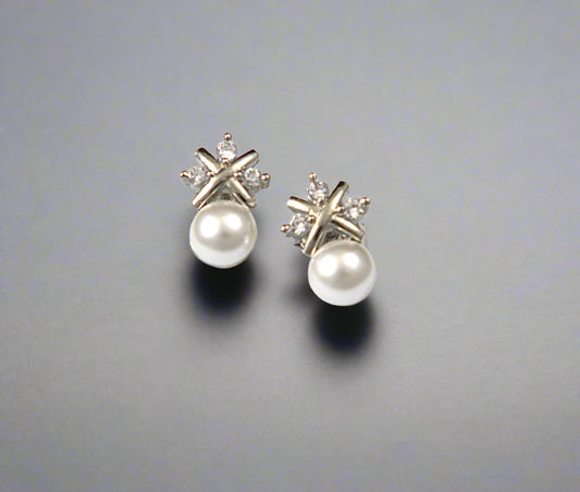 Pair of pearl earrings with star-shaped diamond tops on a white background