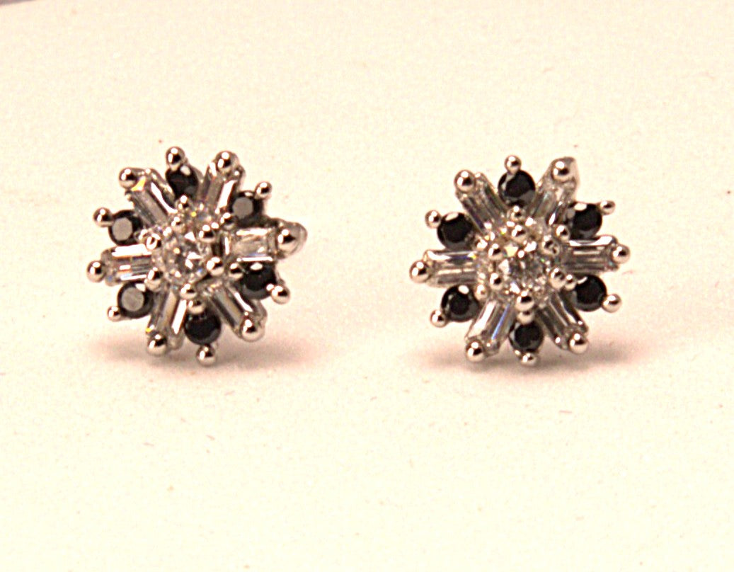 Pair of snowflake-shaped earrings with black and clear gemstones on a light background